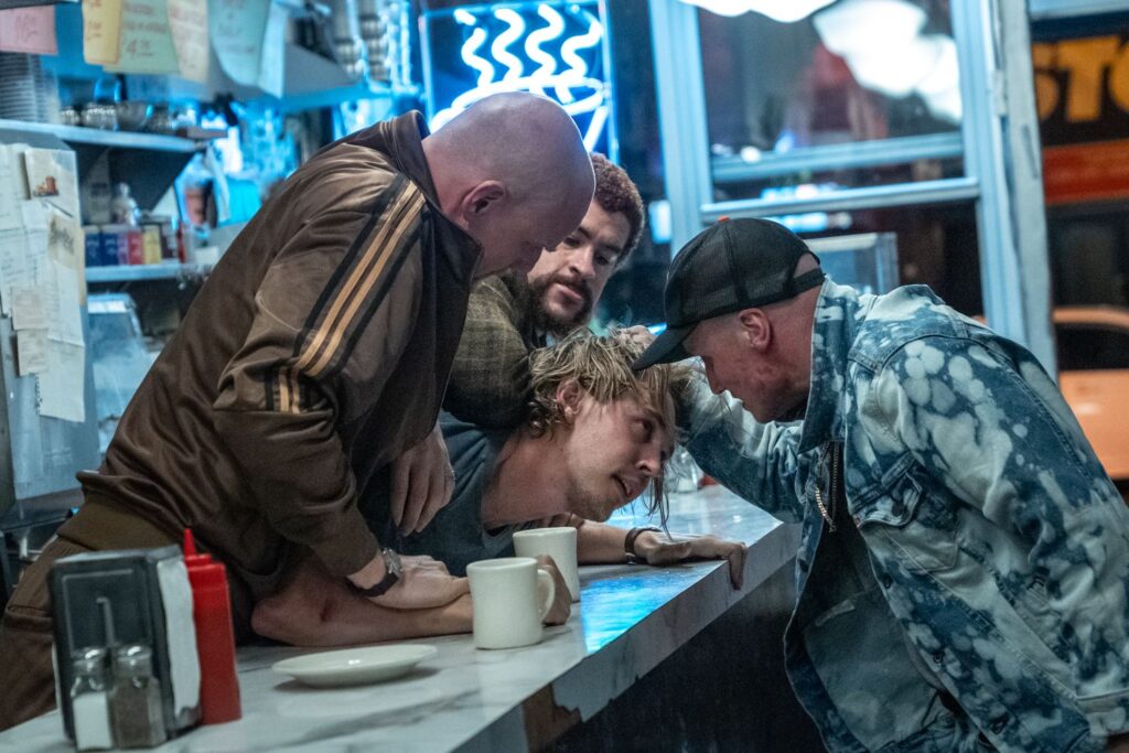 Nikita Kukushkin, Bad Bunny and Yuri Kolokolnikov holding down Austin Butler in a still image from the film