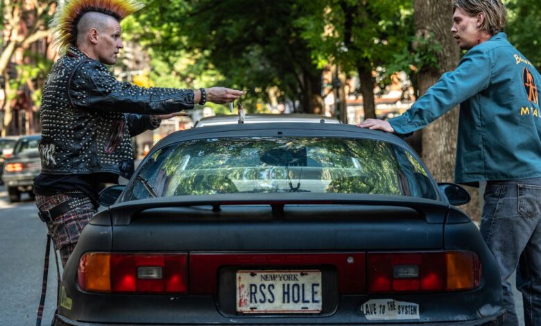 Matt Smith and Austin Butler standing next to a car in a still image from the film