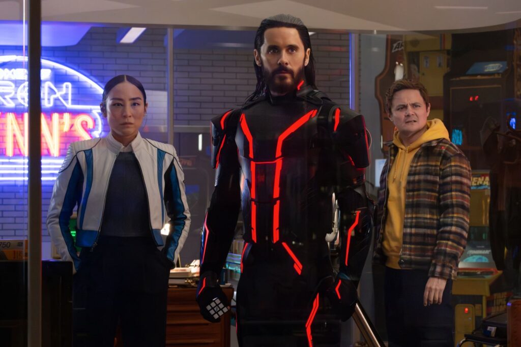 Greta Lee as Eve Kim, Jared Leto as Ares, and Arturo Castro as Seth Flores standing in a still from the movie