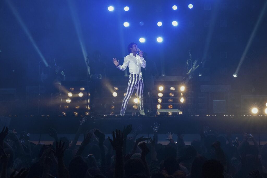 In concert standing on stage, Jaafar Jackson as Michael Jackson in Michael.