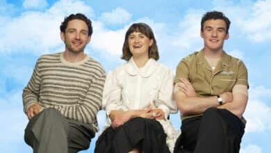Laurie Davidson, Ella Bruccoleri, and Dónal Finn from The Other Bennet Sister sitting in chairs during the interview with a sky background.