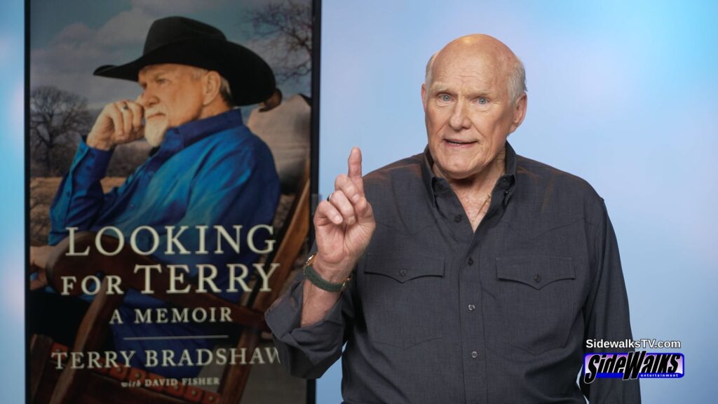Terry Bradshaw with his finger up. His book cover on the monitor behind him.